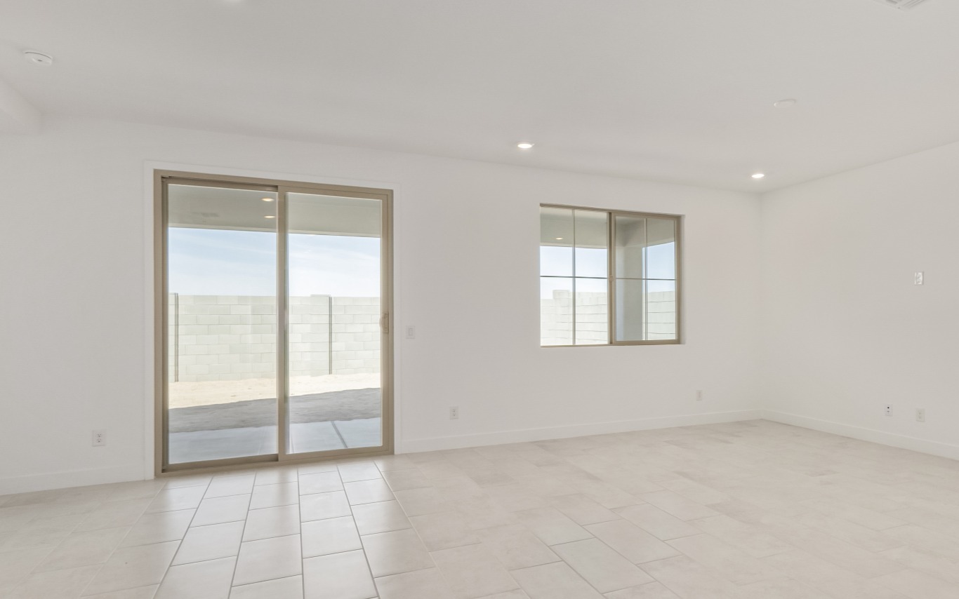 Empty room with white walls, light-colored tile floors, a sliding glass door, and a rectangular window overlooking a block wall.