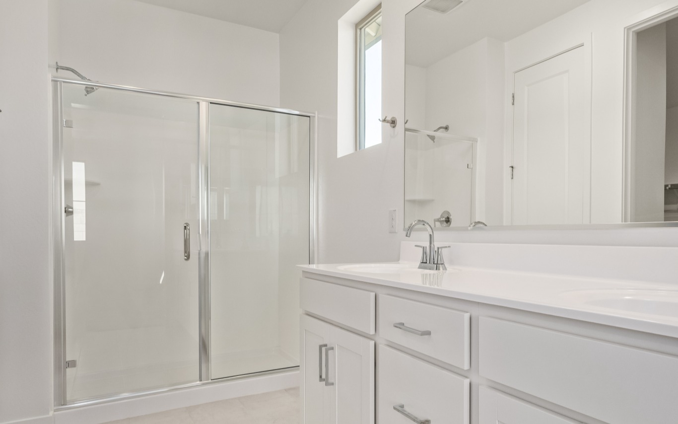 A bathroom with a white vanity, a large mirror, and a glass-enclosed shower.