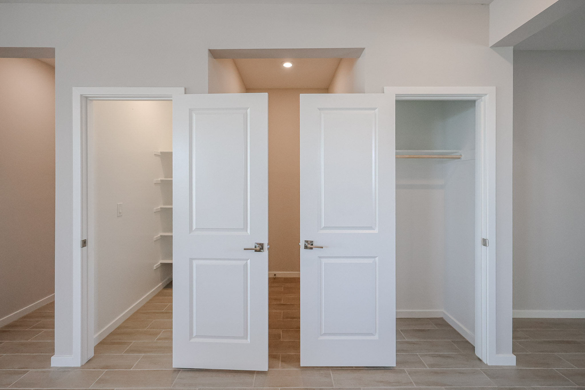 Three open closets with white doors in a modern room; the left closet has shelves, the center closet is empty, and the right closet has a single hanging rod.