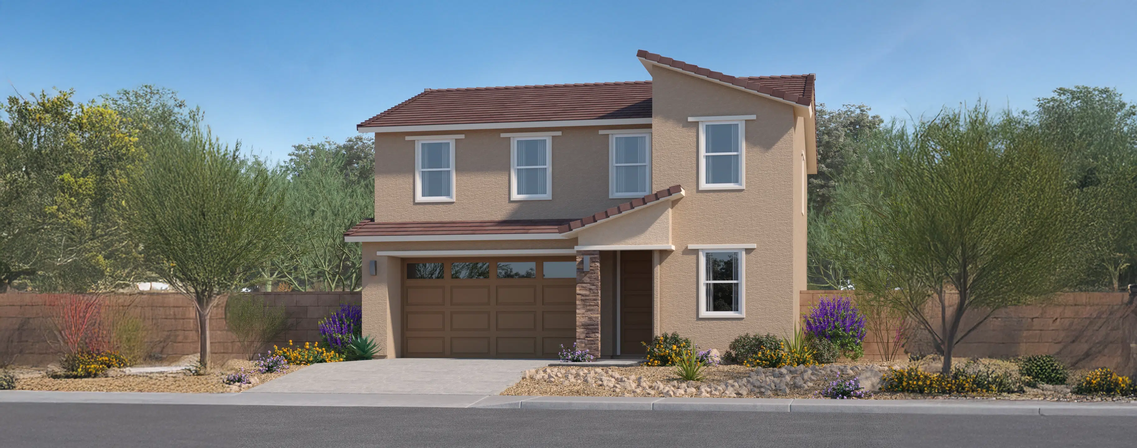 Two-story beige stucco house with a brown tile roof, double garage, small front porch, and desert landscaping with shrubs and flowers.