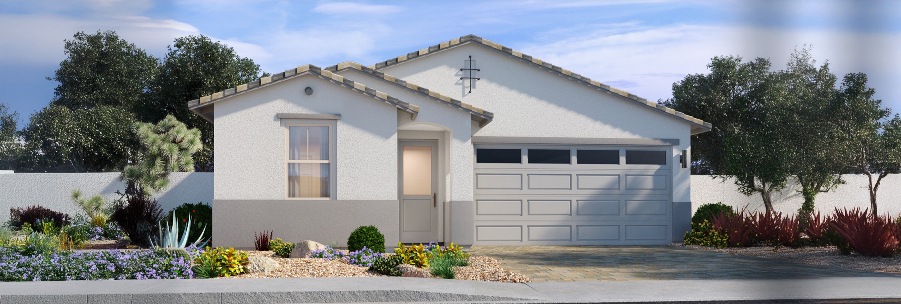 Single-story house with a two-car garage, white exterior walls, tiled roof, and desert landscaping with shrubs and rocks in the front yard.