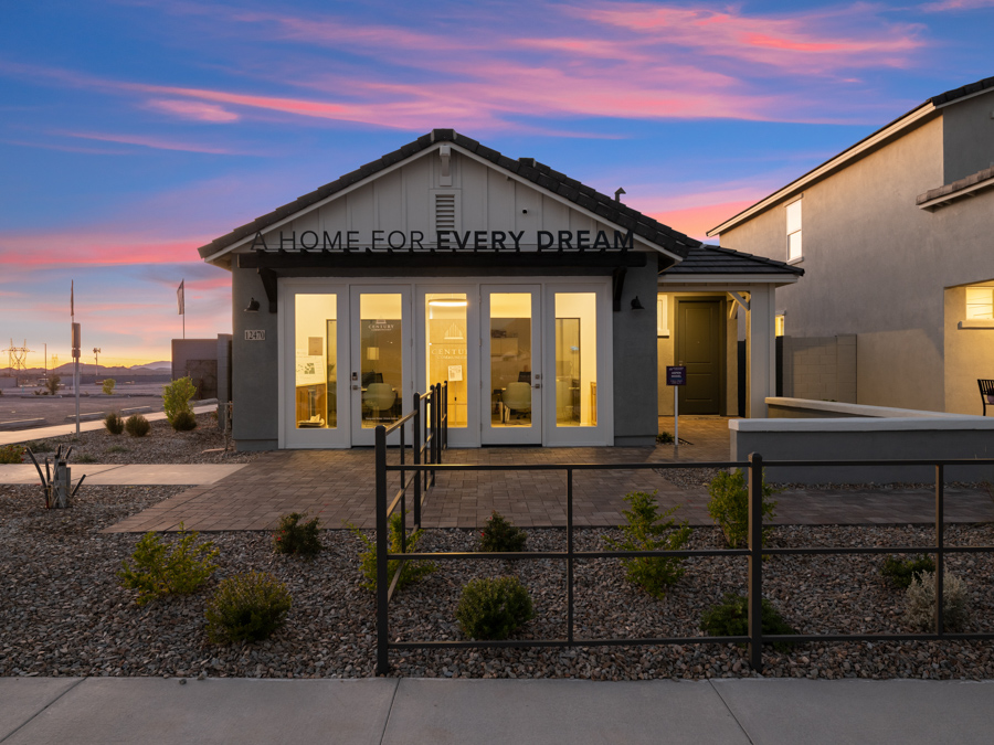 A modern single-story house with large front windows, illuminated at dusk, displays the text “Home For Every Dream” above the entrance.