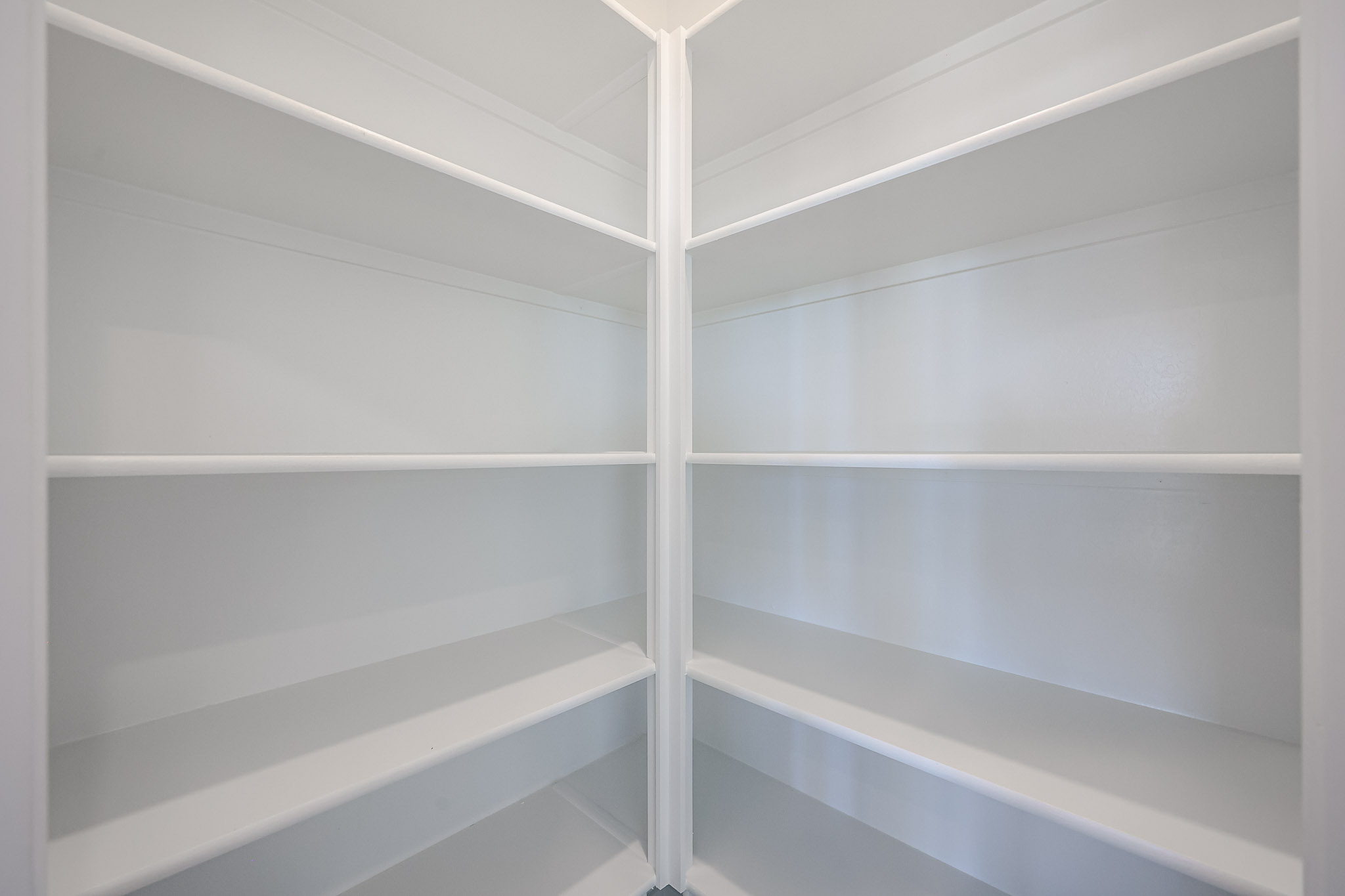 Empty white corner pantry with six shelves on each side.